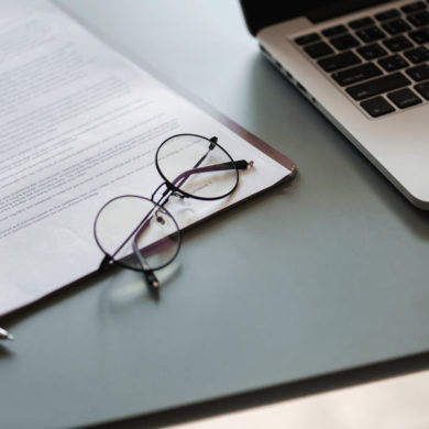 Eye Glasses Rest on Desk Next to Laptop